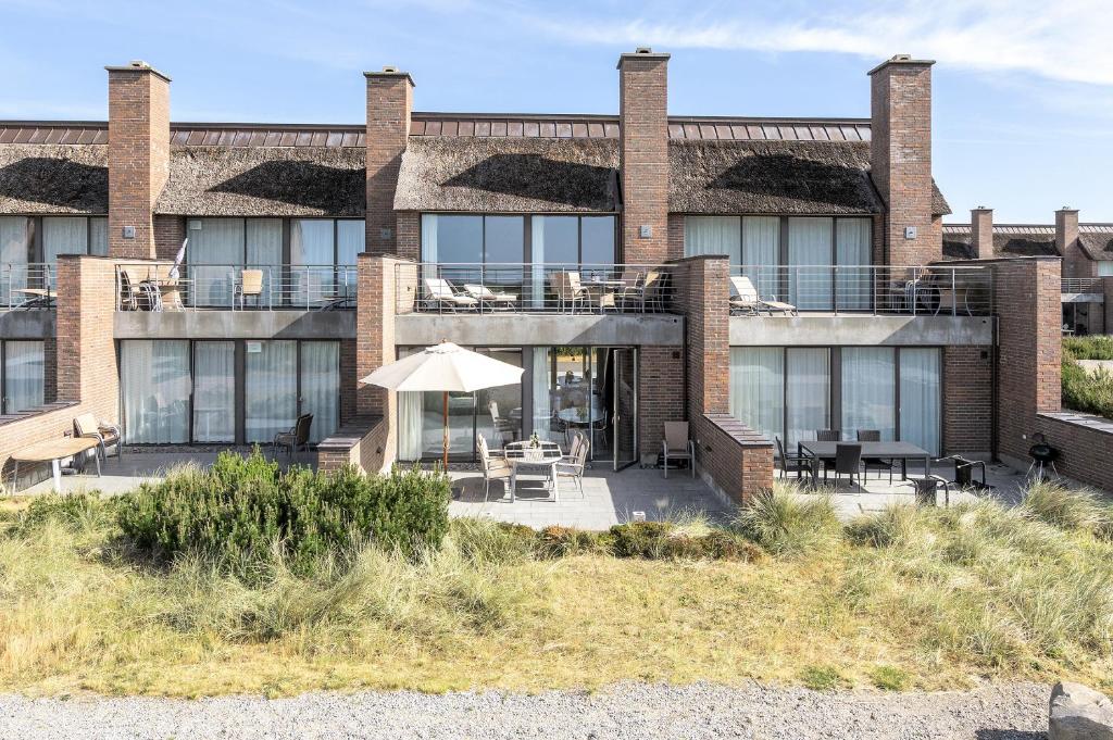 a building with a patio and tables and chairs at Gulirisvej Havneby Rømø in Rømø Kirkeby