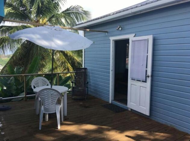 a patio with a table and chairs and an umbrella at Cosy Hut 2 in Saint Georgeʼs