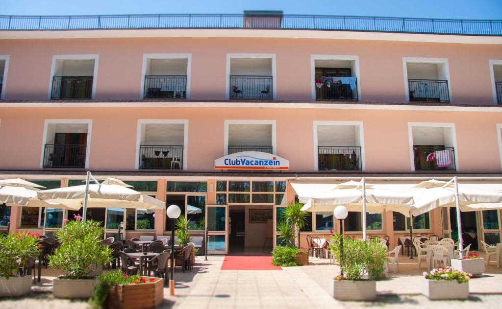 - une vue sur l'extérieur d'un hôtel avec des tables et des parasols dans l'établissement Club Vacanze In, à Cervia