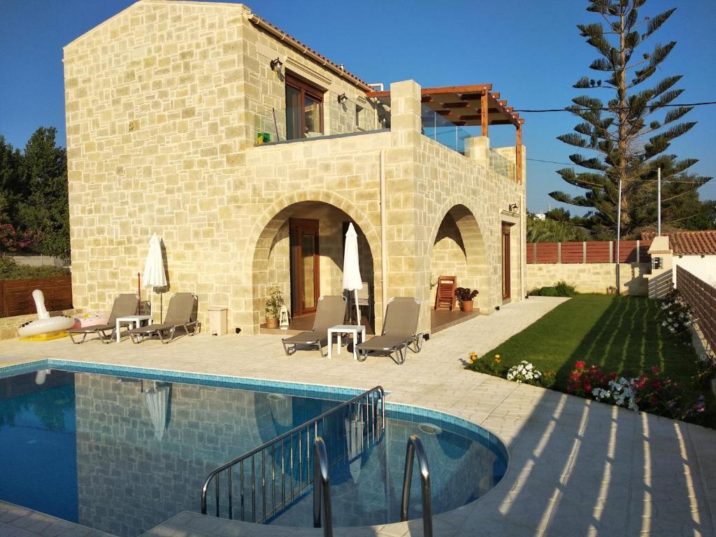 a villa with a swimming pool in front of a house at Villa Katerina in Agia Marina Nea Kydonias