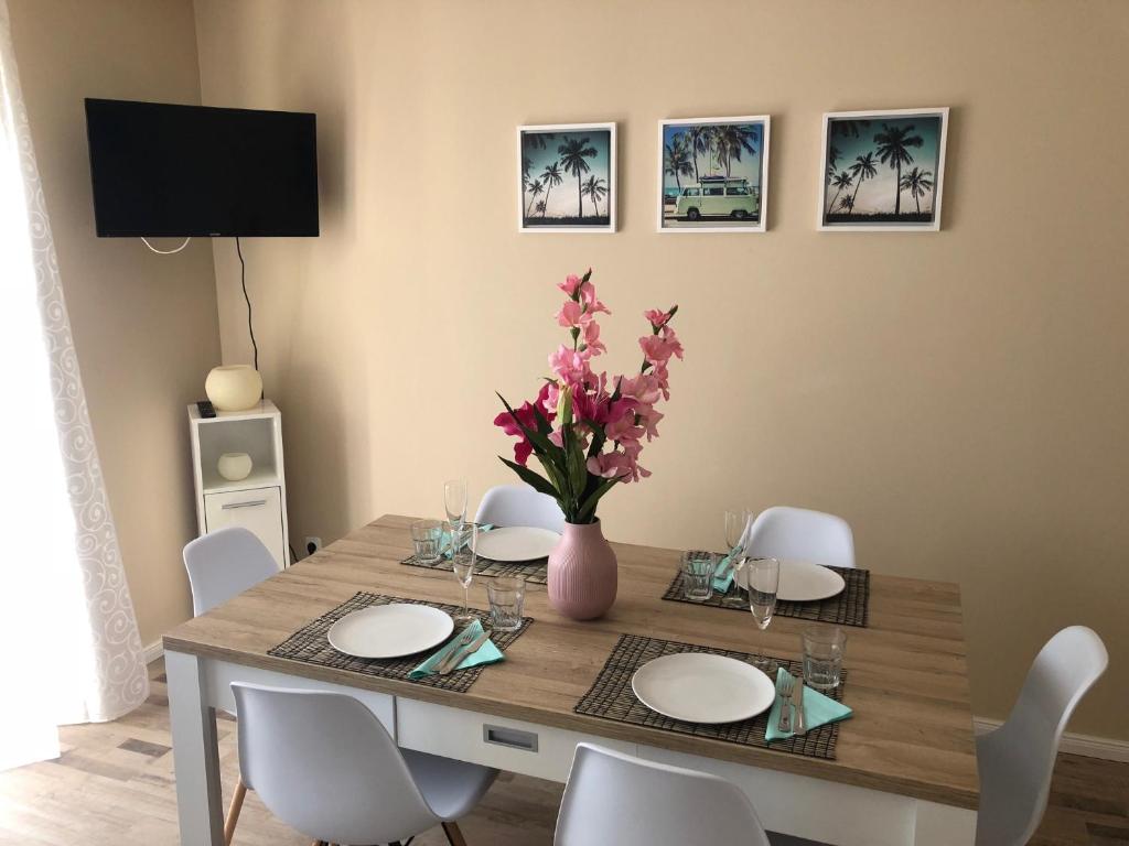 einen Esstisch mit weißen Stühlen und eine Vase mit Blumen in der Unterkunft Monteur Apartment Rodenbach in Rodenbach