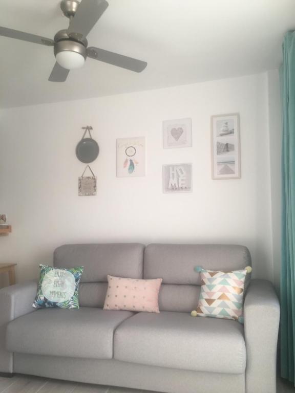 a gray couch in a living room with a ceiling fan at Sunny Apartment Puerto Rico in Puerto Rico de Gran Canaria