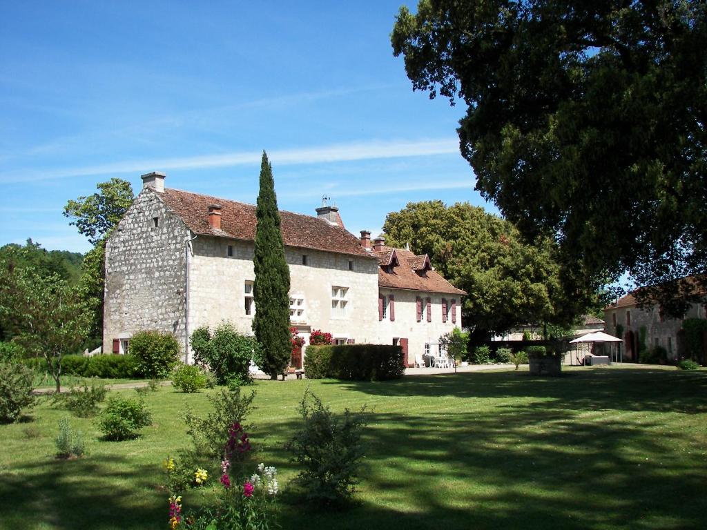 un gran edificio de piedra con un patio con un árbol en Domaine du Noble en Saint-Jean-de-Thurac