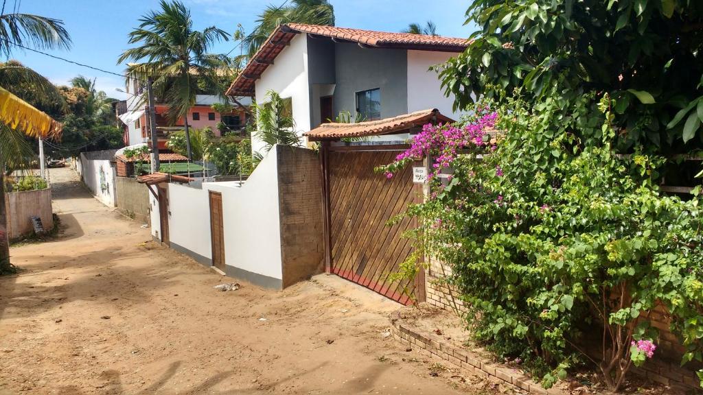 una casa en un camino de tierra con una valla y flores en Casa de Nylva Beach Pipa, en Pipa