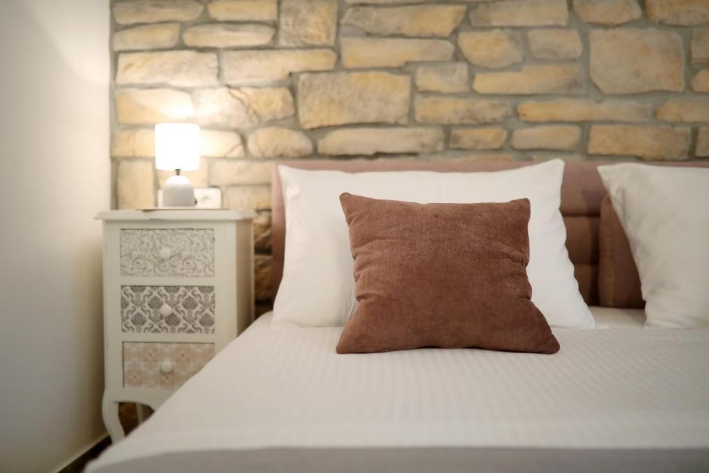 a bed with a pillow and a stone wall at Saint Simeon room and apartment in Zadar
