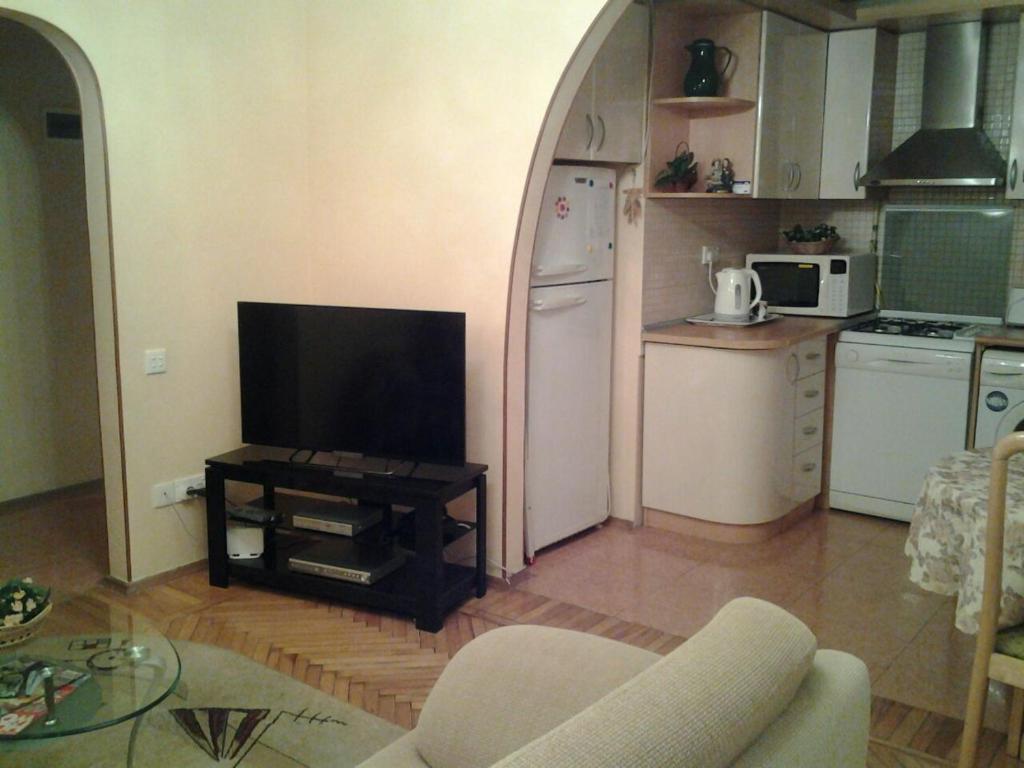 eine Küche mit einem Wohnzimmer mit einem Tisch und einem TV in der Unterkunft Metro SAHIL Seaside Centr in Baku