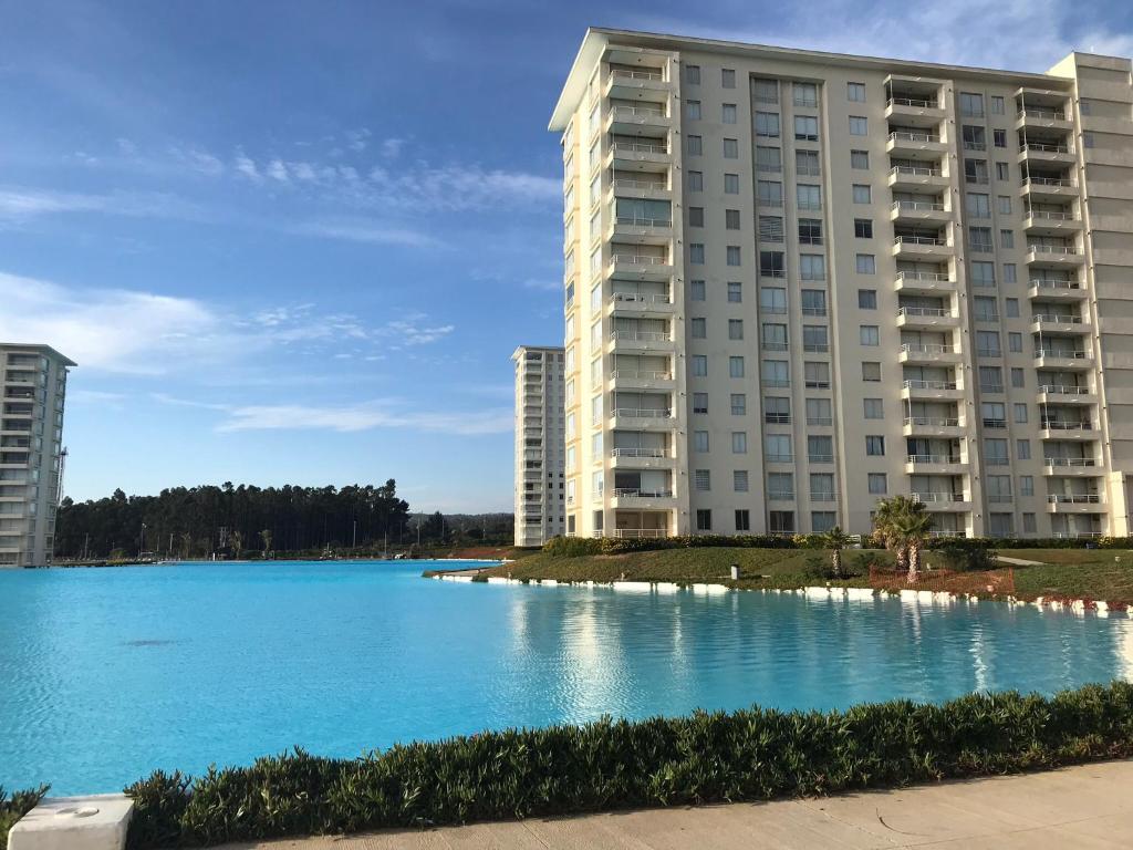 un gran lago azul frente a un edificio en Laguna Bahía Algarrobo, en Algarrobo