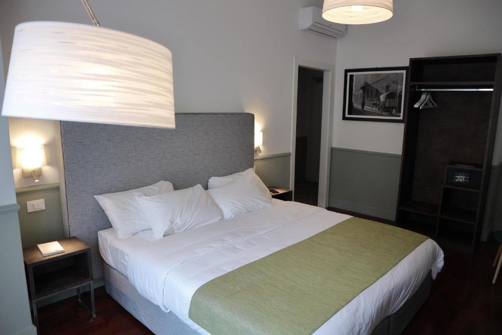 una camera da letto con un grande letto bianco con una grande testiera del letto di Dimora dell'Arte - Foresteria lombarda Smart Rent a Sesto San Giovanni