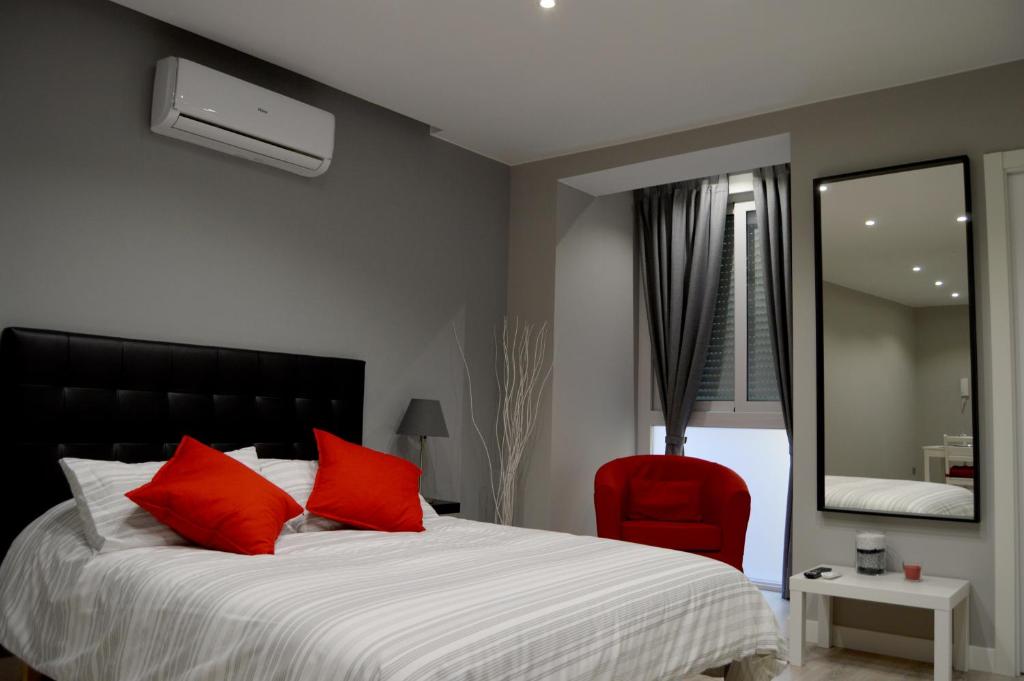 薩拉戈薩的住宿－Apartamenticos Estudio Las Armas，一间卧室配有一张带红色枕头和镜子的床