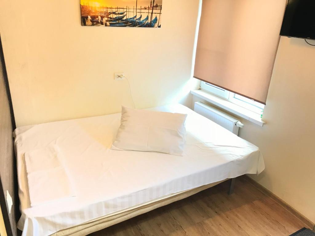 ヴォルゴグラードにあるApartment 39Gvardeyskoyの窓付きの小さな客室で、白いベッドが備わります。