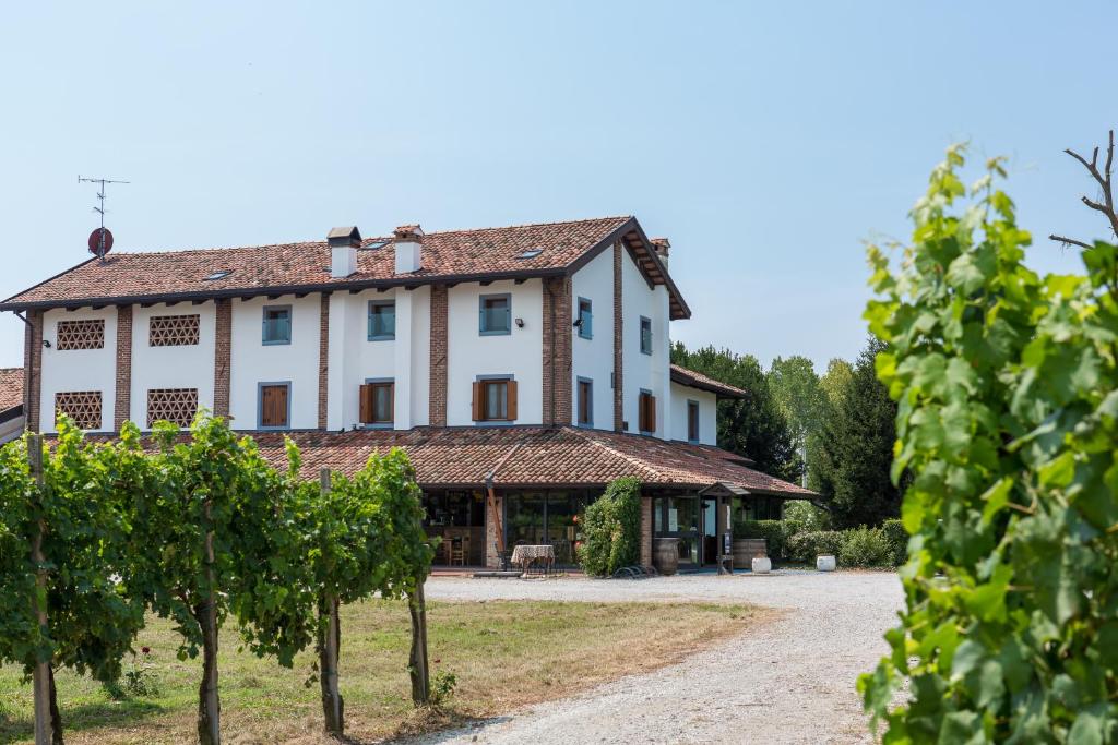 un grande edificio bianco con alberi di fronte di Agriturismo Cjasal di Pition a Pozzuolo del Friuli