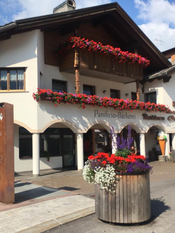 a building with a bunch of flowers in a barrel at Residence Ploner in San Cassiano