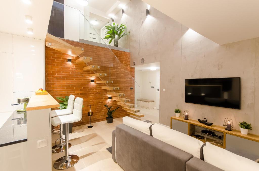 een woonkamer met een bank en een tv en een bakstenen muur bij Central Penthouse with terrace in Krakau