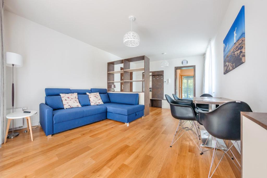 ein Wohnzimmer mit einem blauen Sofa und einem Tisch in der Unterkunft Apartamenty Sun & Snow Leśne Zacisze in Świnoujście