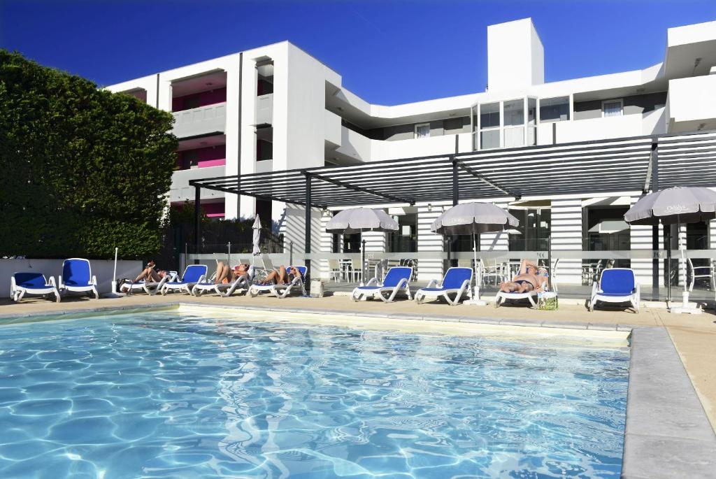 a group of people sitting in chairs by a swimming pool at Résidence Odalys Aqualia in Balaruc-les-Bains