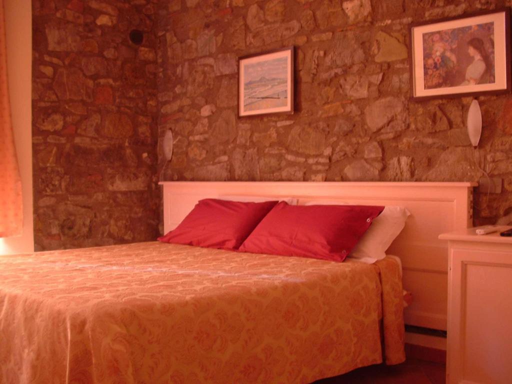 1 dormitorio con 1 cama con almohadas rojas en Locanda Il Gallo en Greve in Chianti