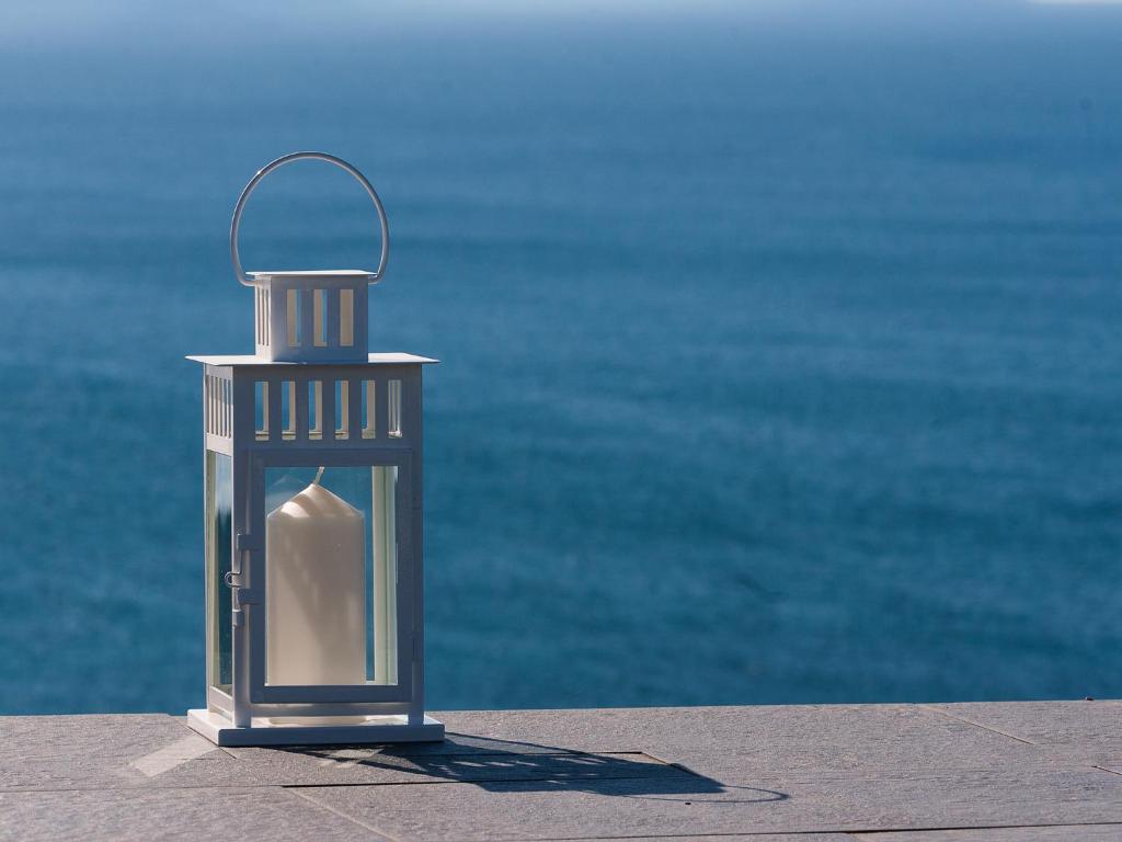 una lanterna di metallo seduta su un marciapiede accanto all'acqua di Casa Maravilla a Faro de Peñas