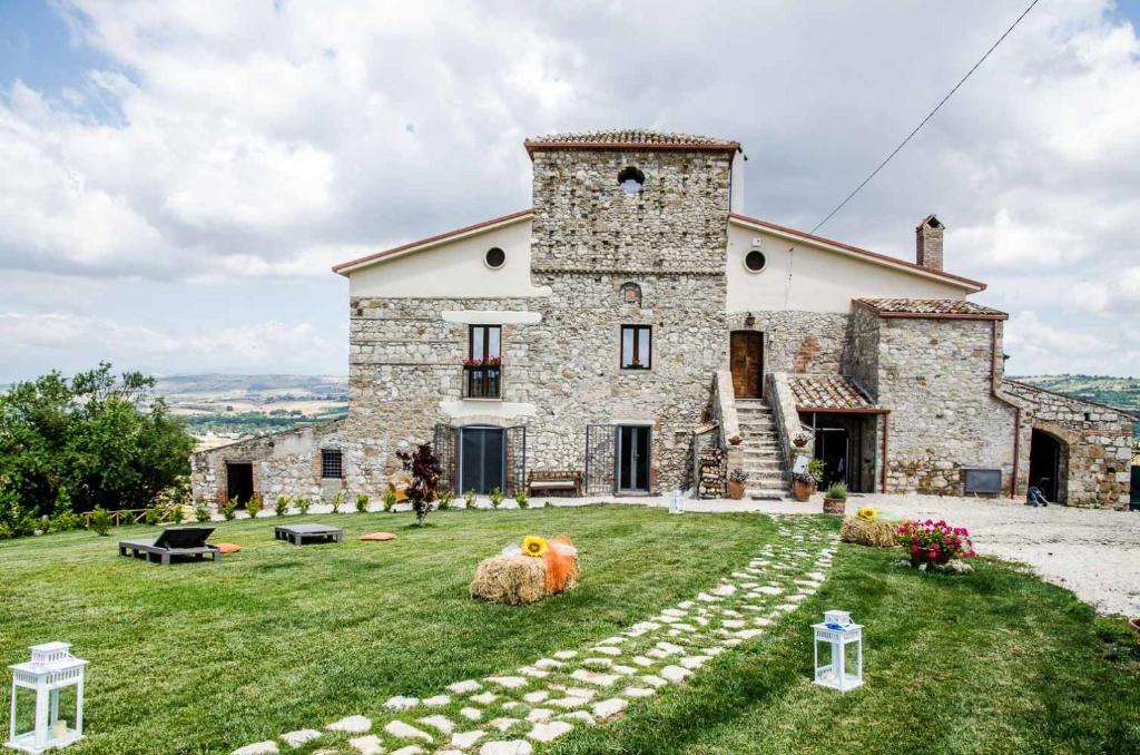 uma grande casa de pedra com dois grandes animais no relvado em Country Relais La Torretta Baronale em San Giorgio del Sannio