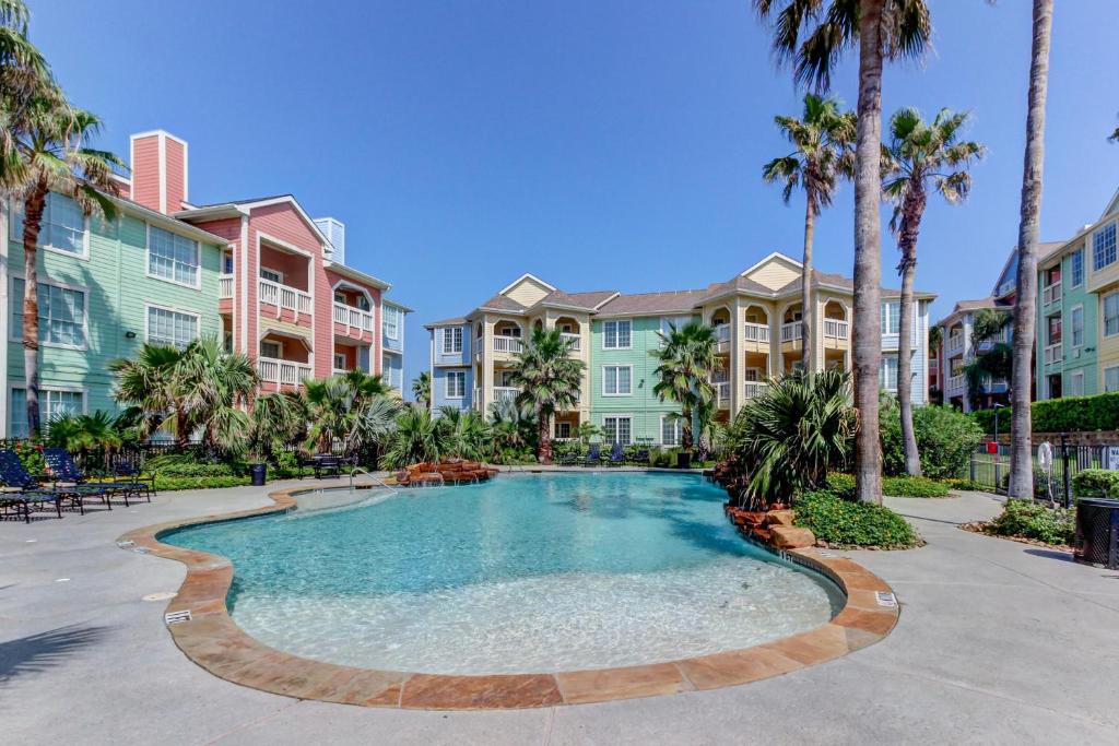 una piscina con palmeras y apartamentos en condominio en The Dawn Condominiums, en Galveston