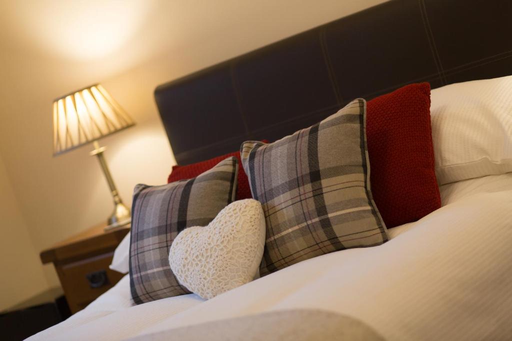 um quarto com uma cama com almofadas e uma almofada de coração em Cedars Guest House em Aberdeen