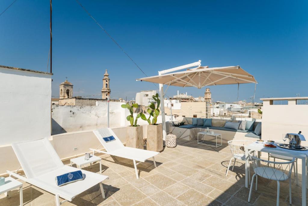 a patio with white chairs and an umbrella on a roof at Dimora Maio in Monopoli