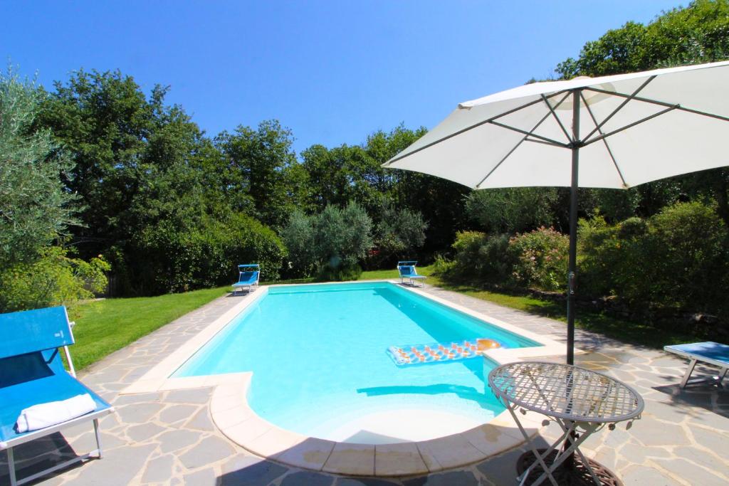 uma piscina com um guarda-sol e cadeiras e uma mesa e um guarda-sol em Villa Gioiosa em Monte San Savino