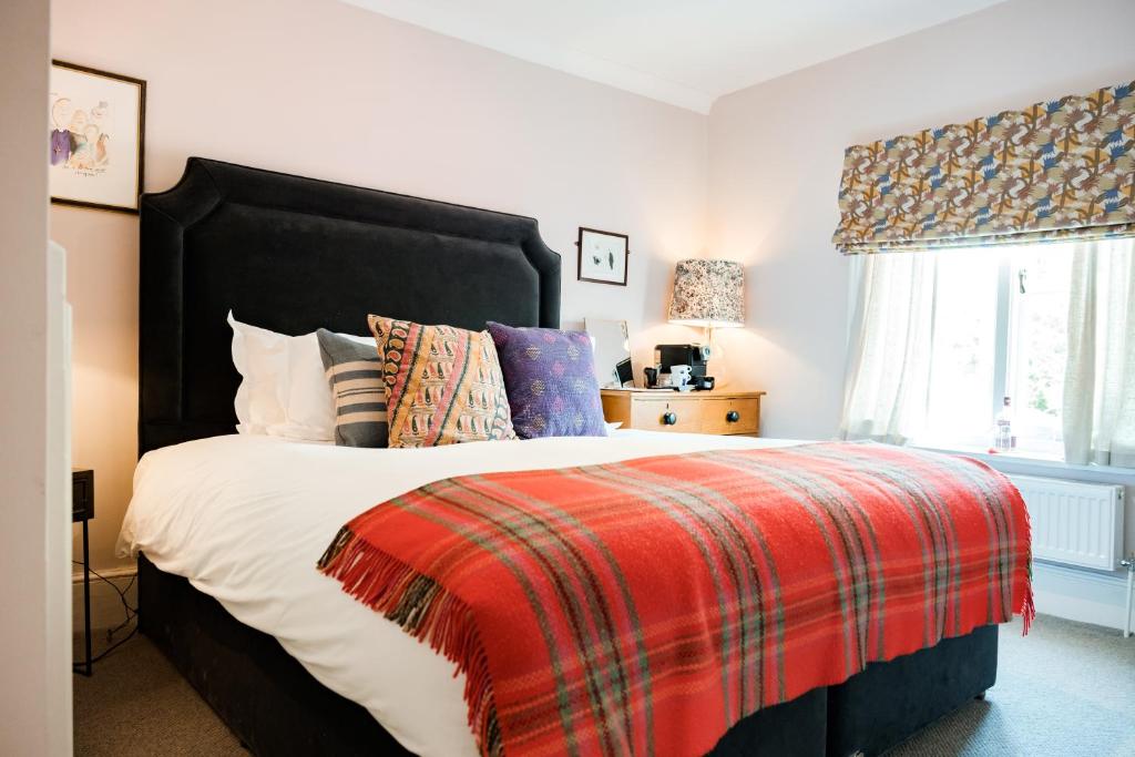 a bedroom with a large bed with a red blanket at Bel and The Dragon-Cookham in Cookham