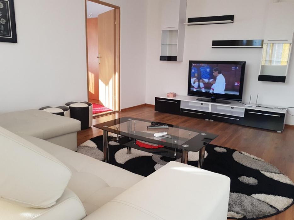 a living room with a white couch and a tv at Apartament Central Miguel in Turda