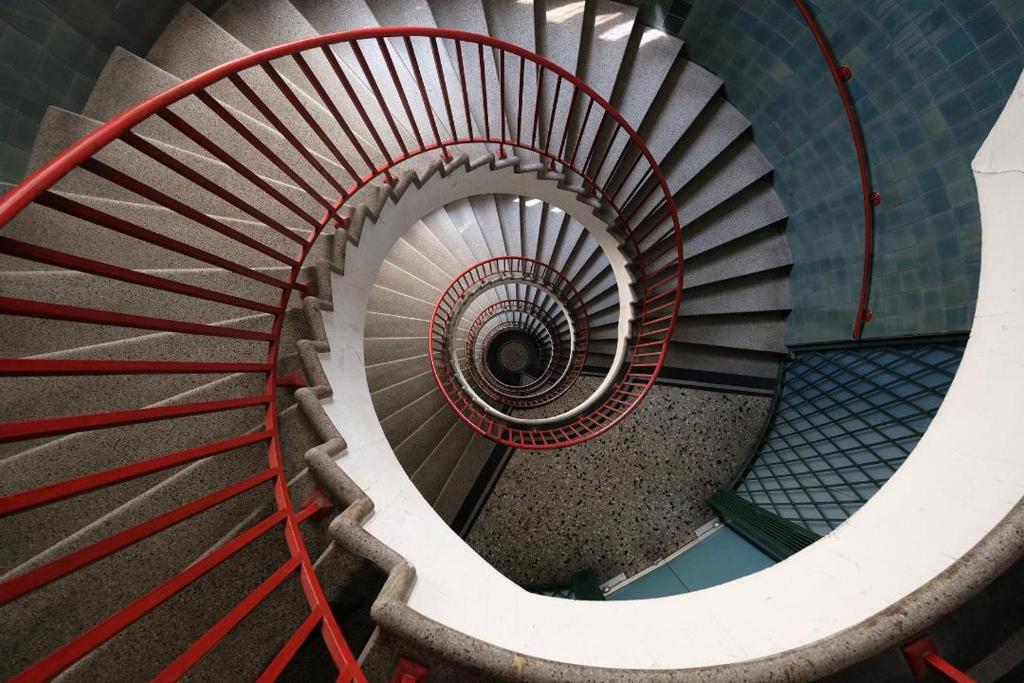 eine Wendeltreppe mit rotem Geländer in einem Gebäude in der Unterkunft Lawyers Loft in Heritage Skyscraper in Ljubljana