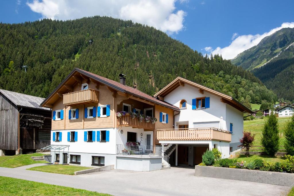 ein Haus mit blauen Fenstern und einem Berg in der Unterkunft Ferienwohnung Schallner in Sankt Gallenkirch