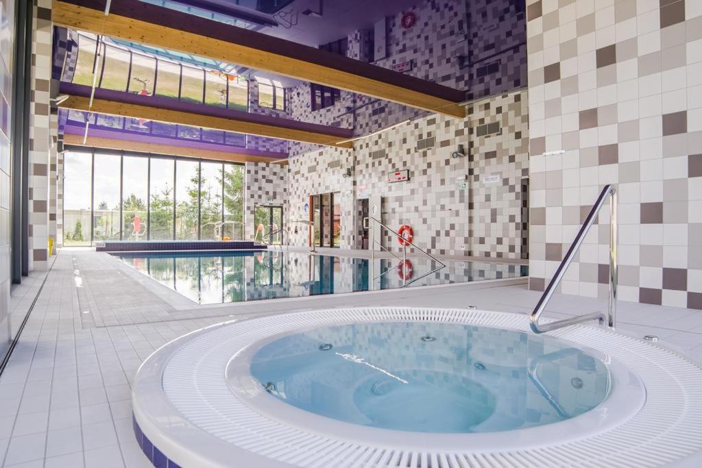 a hot tub in a room with a swimming pool at Apartamenty 5 mórz in Sianozety