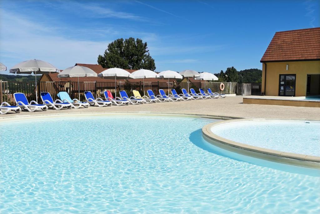- une piscine avec des chaises longues et un groupe dans l'établissement Résidence Odalys - Les Coteaux de Sarlat, à Sarlat-la-Canéda