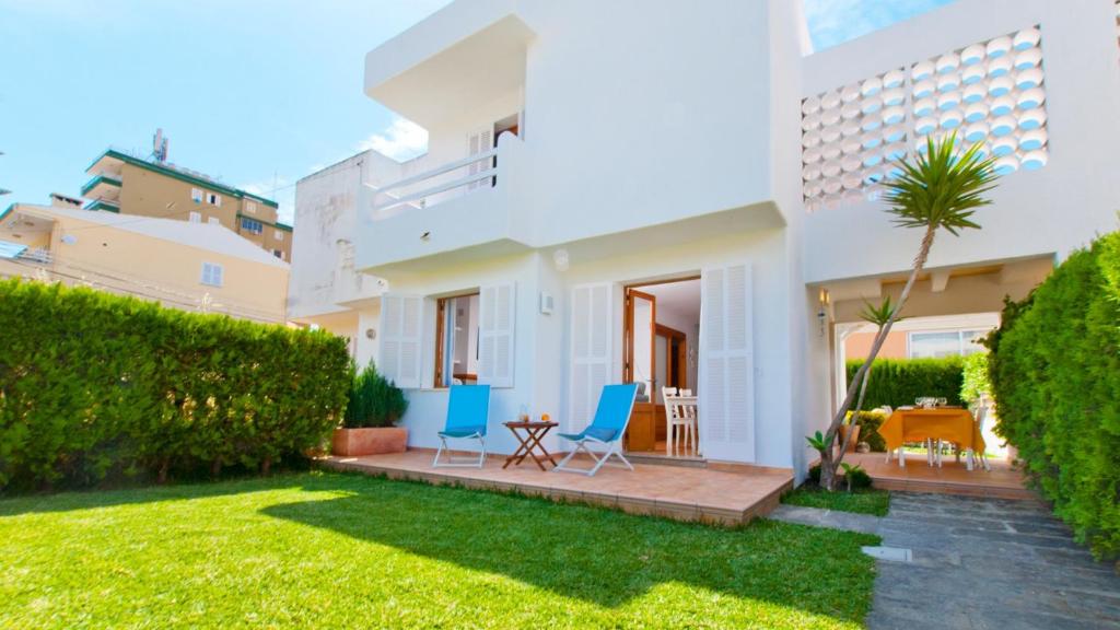 a house with a yard with two chairs and a patio at Casa GAVINES Alcudia in Playa de Muro