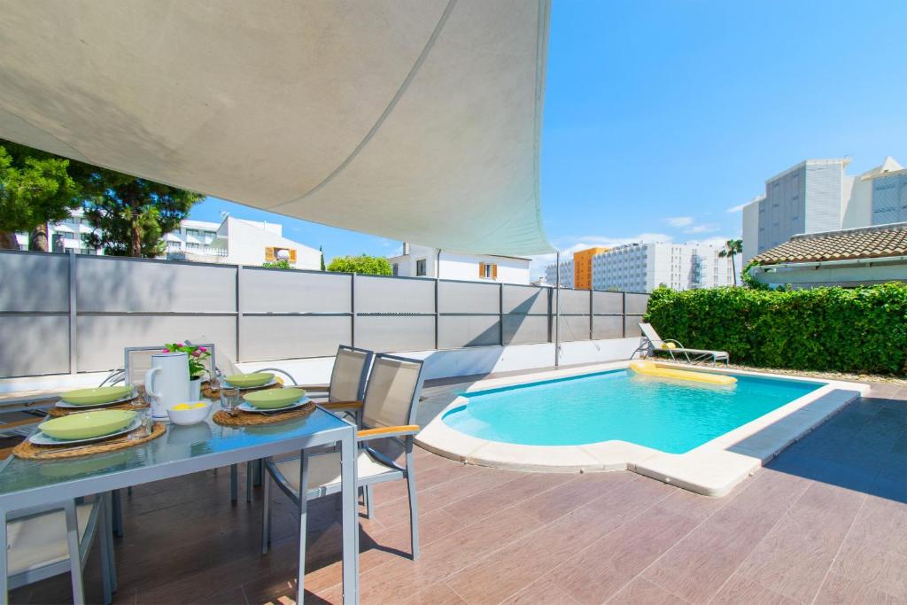 un patio con una mesa y una piscina en Villa NICO beach ALCUDIA, en Alcudia