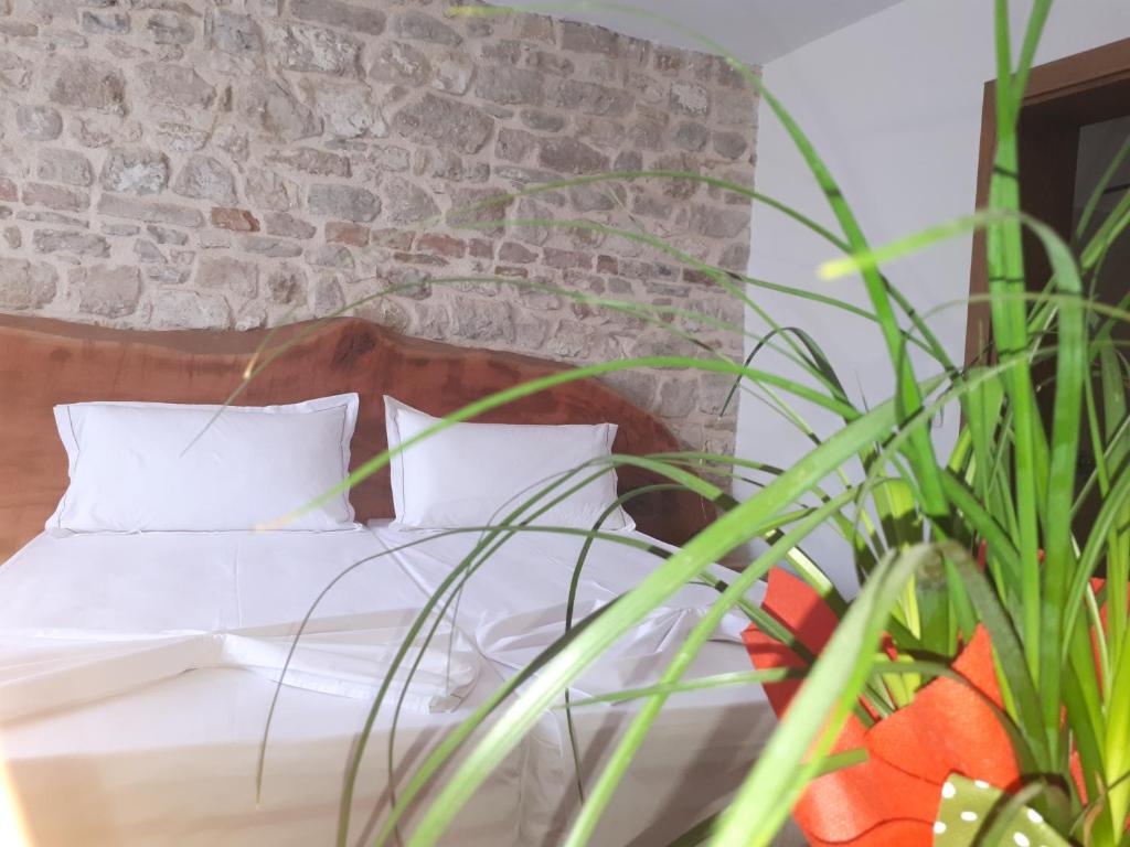 a bed with white sheets and pillows next to a brick wall at Hotel Omer The Ottoman House in Berat