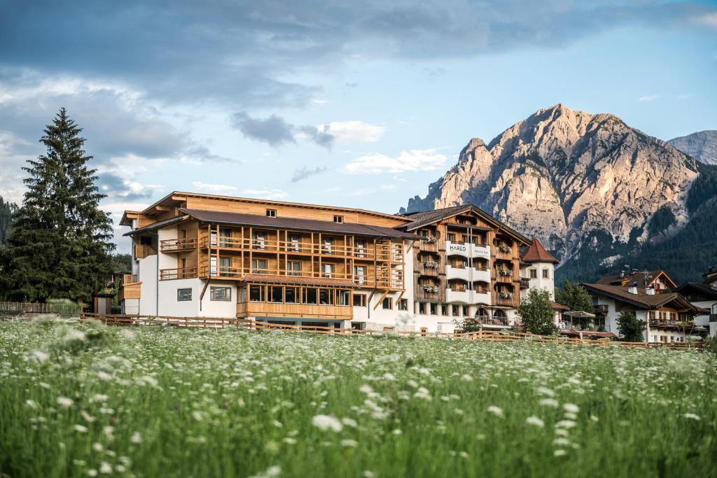 a large building with mountains in the background at Dependance Hotel Mareo Dolomites in San Vigilio Di Marebbe