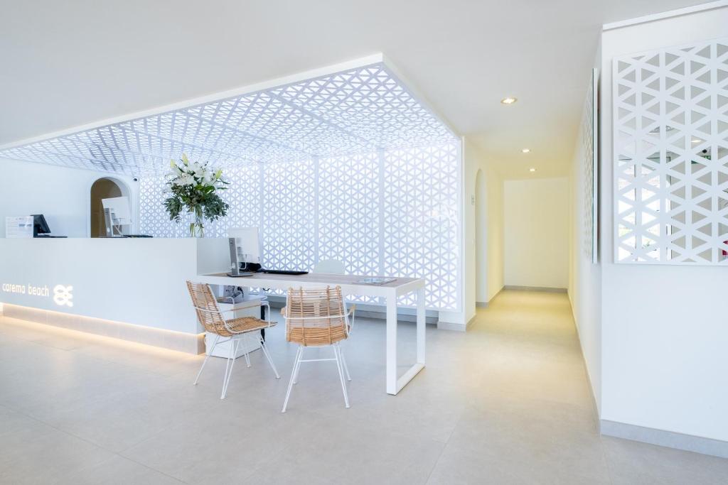 a white dining room with a white table and chairs at FERGUS Style Carema Beach in Cala en Bosc