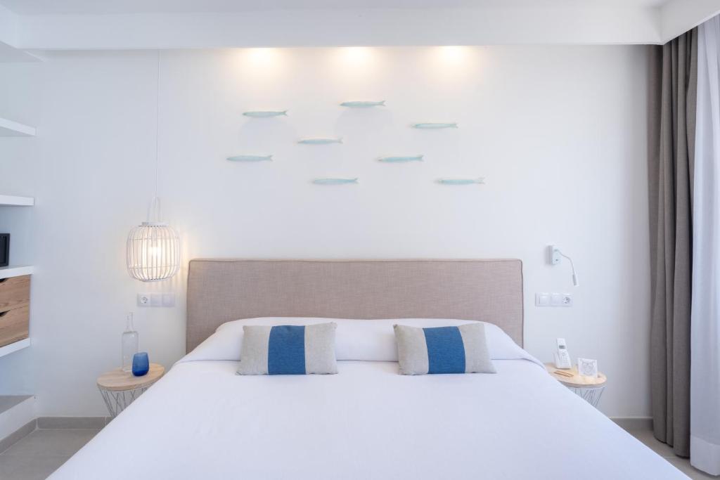 a bedroom with a white bed with blue and white pillows at FERGUS Style Carema Beach in Cala en Bosc