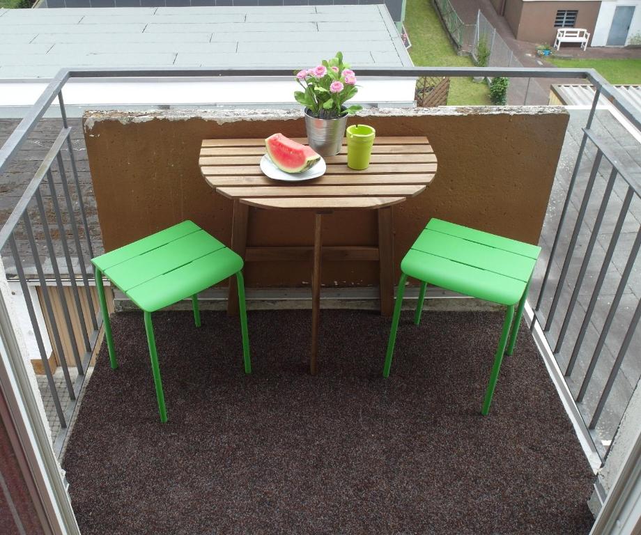 een tafel en stoelen op een balkon met een stuk watermeloen bij Sympathisches Retro Apartment in Offenbach