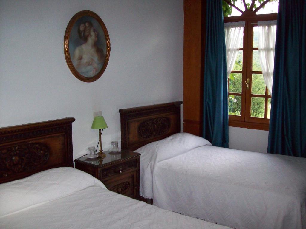 a bedroom with two beds and a mirror on the wall at Hotel Rural La Lastra in Caso