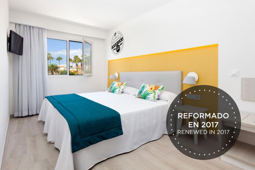 a hotel room with a bed with a blue blanket at Hotel Tropical Park in Callao Salvaje