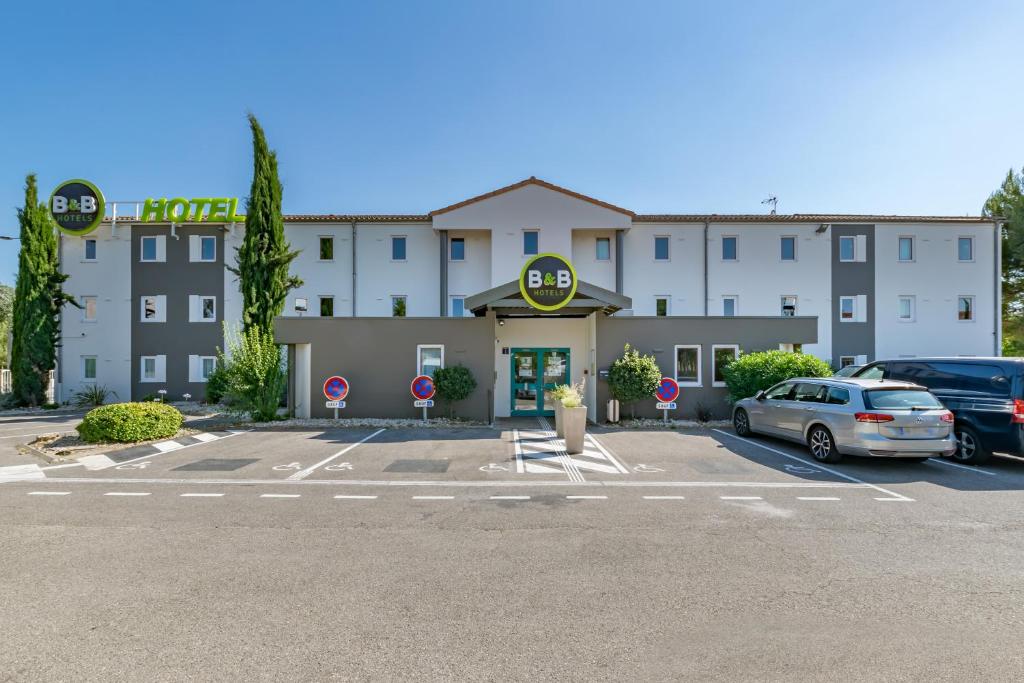 un hôtel avec des voitures garées dans un parking dans l'établissement B&B HOTEL Aix-en-Provence Pont de l'Arc, à Aix-en-Provence