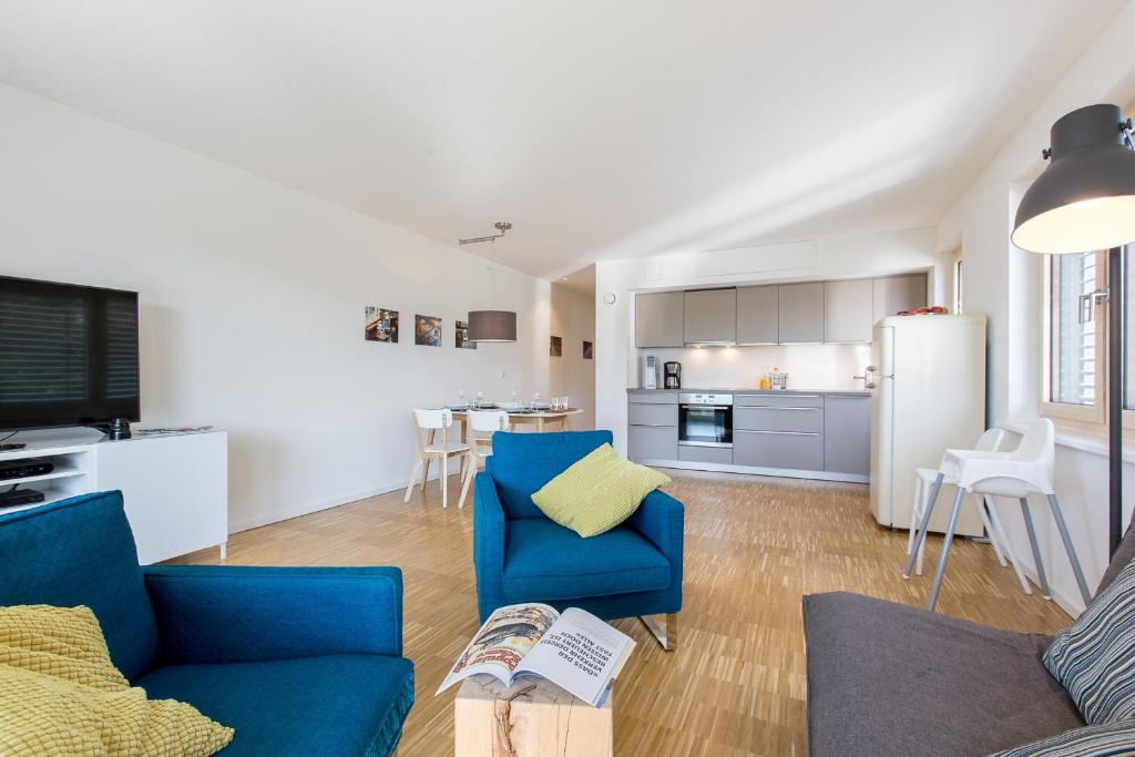 ein Wohnzimmer mit einem blauen Sofa und einer Küche in der Unterkunft Ferienwohnung Busch in Friedrichshafen