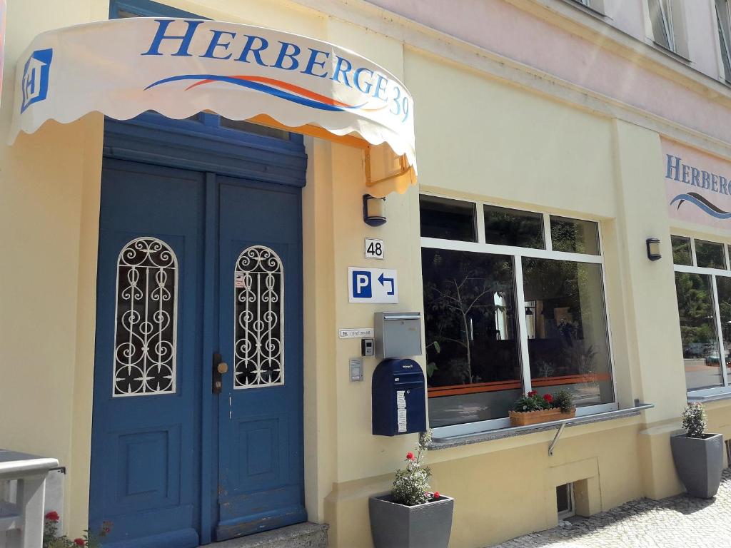 un magasin avec une porte bleue et un panneau herzinger dans l'établissement Herberge 39, à Meissen