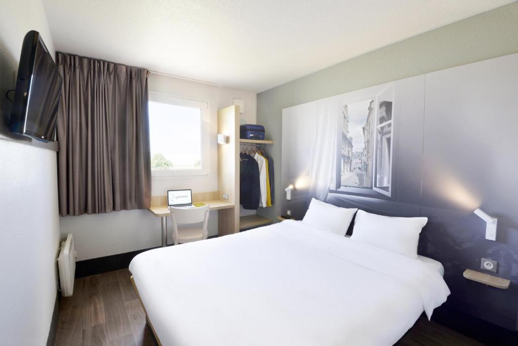 een slaapkamer met een groot wit bed en een raam bij B&B HOTEL Bourges 2 in Bourges