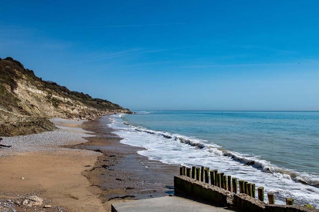 einen Strand mit einem Zaun und dem Meer in der Unterkunft Whitecliff Bay Holiday Park in Bembridge