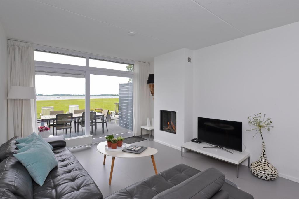 Una sala de estar con un sofá, un televisor y una mesa. en Havenweg 12 - direct aan het Veerse Meer, en Kamperland
