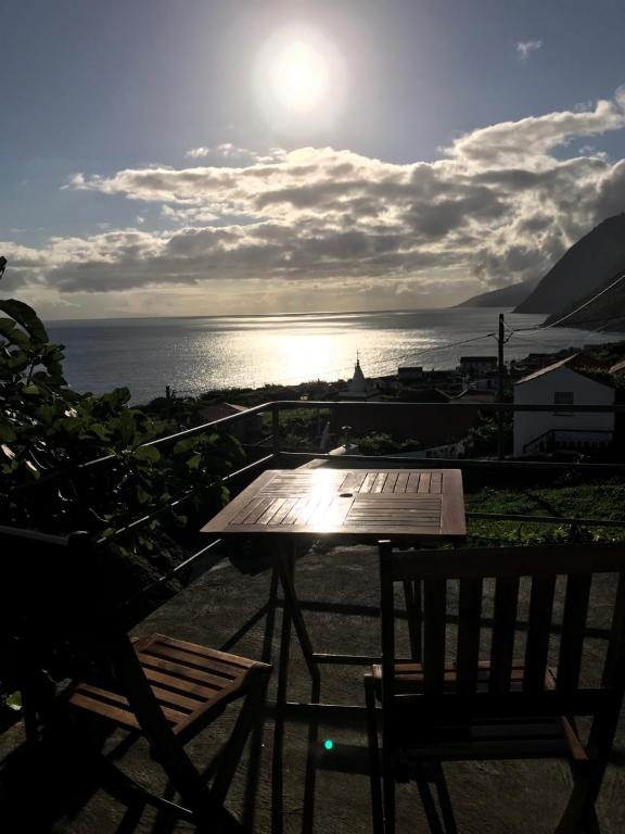una mesa y sillas en un balcón con vistas al océano en A Casa do Avô Coelho, en Santo Antão