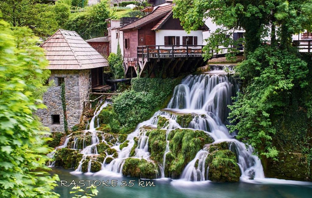 una cascada frente a una casa junto a un río en Apartman Lena en Tušilović