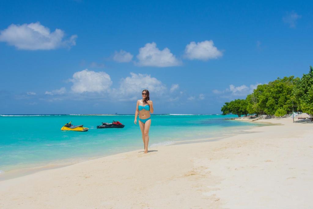 a woman in a blue bikini standing on a beach at Sandy Heaven Maldives in Gulhi